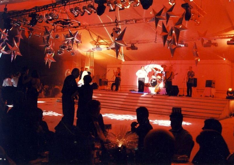 Red-lit venue with hanging silver stars and a live band on stage