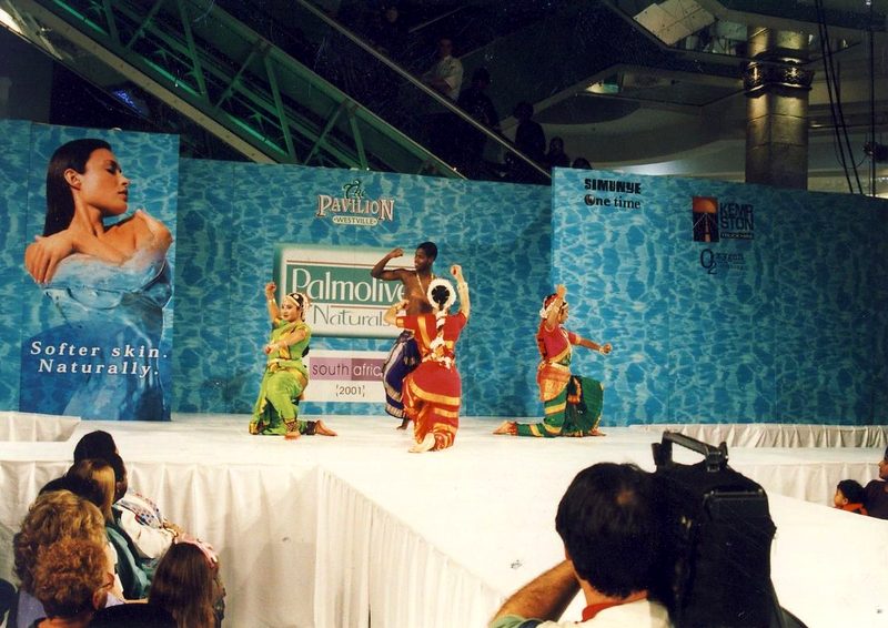 Indian dance performance on a mall stage with a blue water-print backdrop
